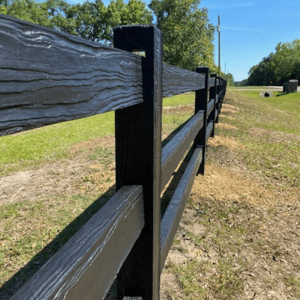 Close-up of precast concrete ranch rail fence detail showing realistic wood-grain texture and steel-reinforced construction